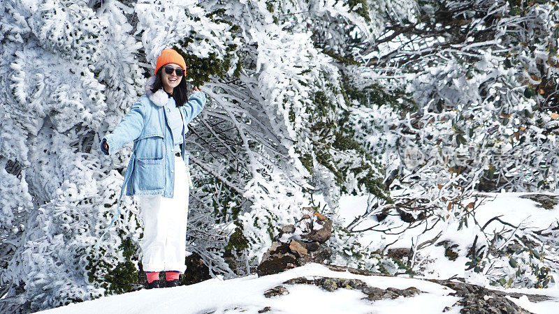 一个女人在寒冷的天气里穿行于白雪覆盖的山林之中