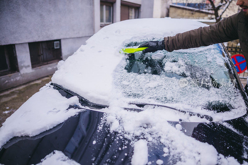 年轻人正在清除汽车上的积雪