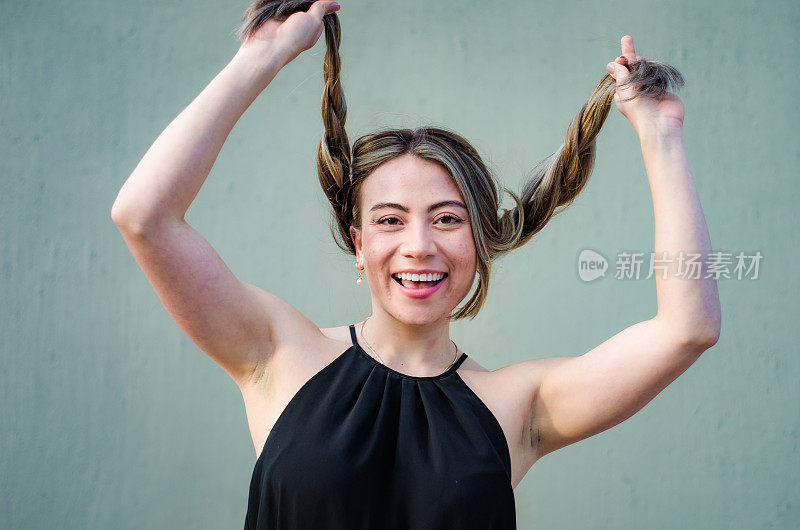 美丽的年轻女子的肖像玩她的头发在灰色背景