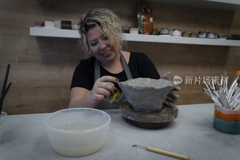 女陶工在陶轮上用湿粘土制成的围裙状花瓶里
