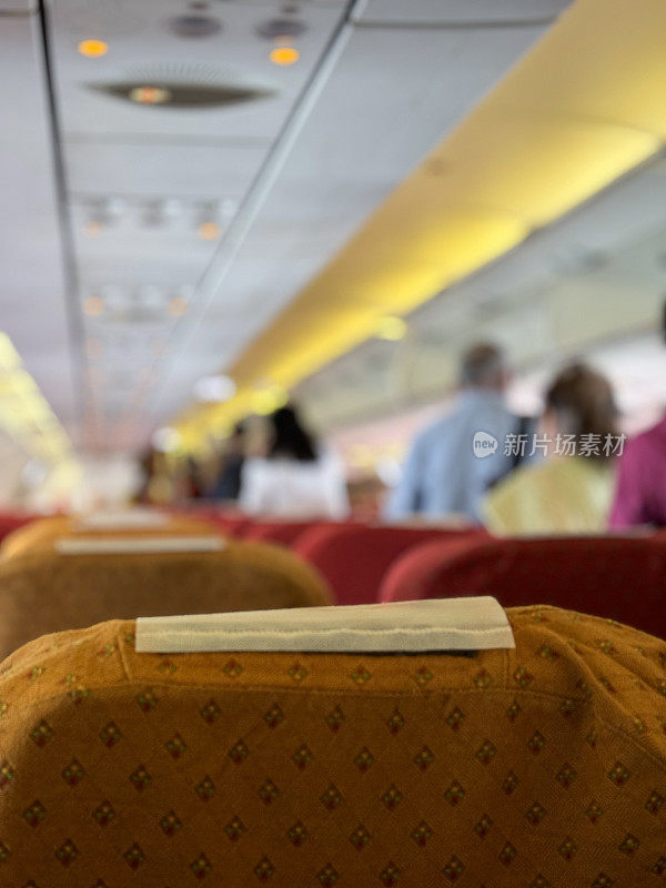 飞机座椅头枕，客机经济舱顶置通风控制台特写图像，照明禁止吸烟标志，缩小视角，人们下飞机，聚焦前景