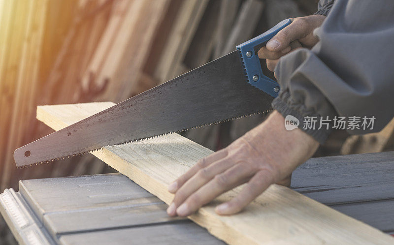 用手锯切割木板的木匠
