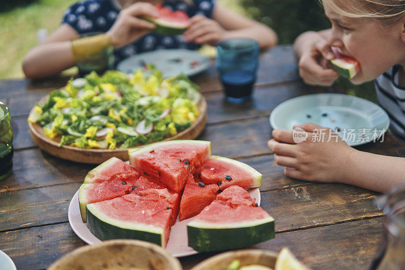 小孩子在外面的花园里吃新鲜的西瓜