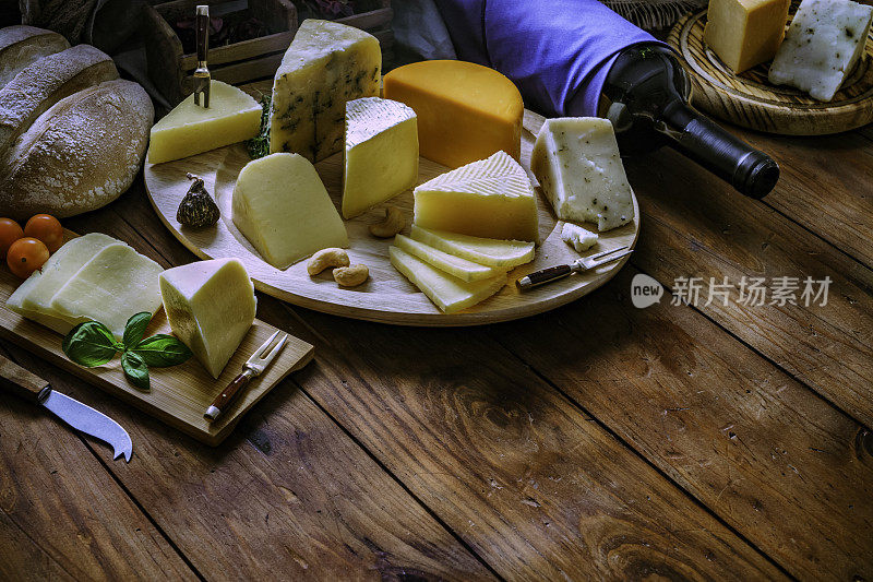 各种各样的奶酪小吃放在一张质朴的木桌上