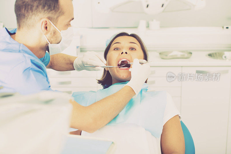 牙医正在治疗一位坐在牙科椅上的女病人