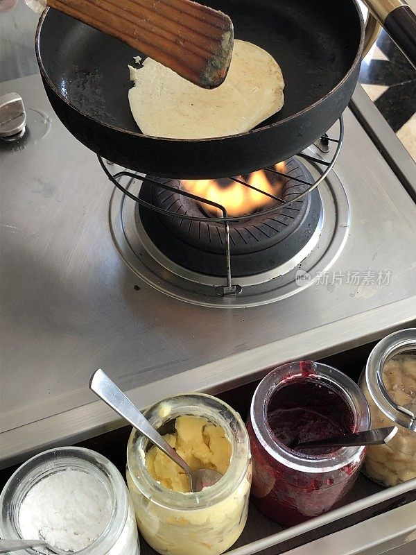 形象的酒店餐厅早餐厨师烹饪自制美式煎饼食谱不粘饼煎饼煎饼煎锅，露营煤气炉炉架，糖和果酱罐，果汁水果，柠檬凝乳，糖粉，煎饼的早餐招待