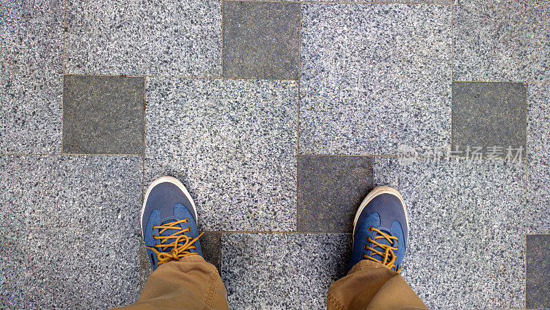 脚放在瓷砖上。脚踩在灰色的水泥砖上。