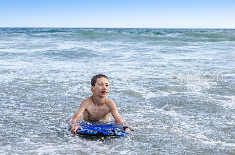 小男孩带着小冲浪板在海滩上