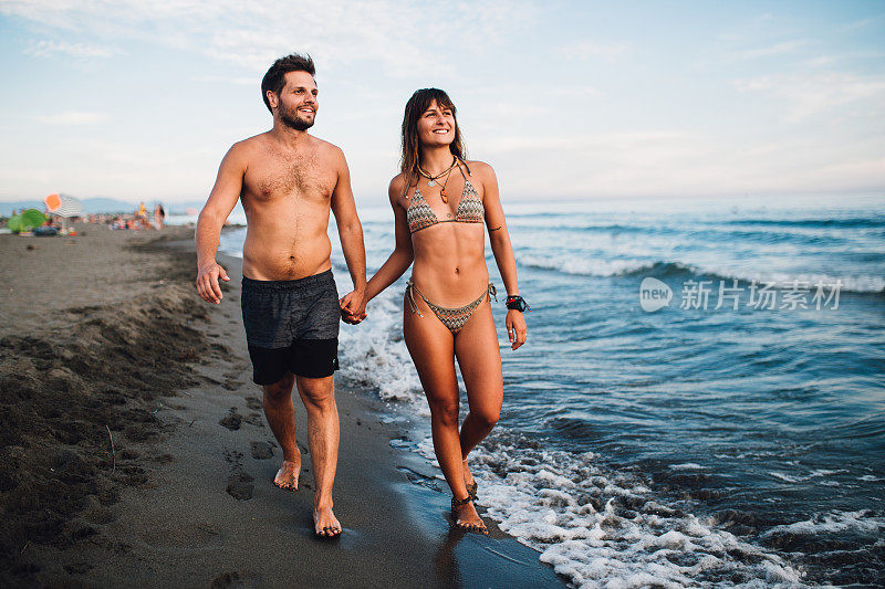 年轻夫妇在海滩上散步，享受