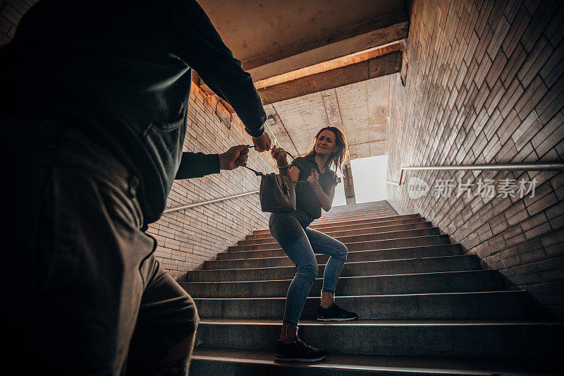 一位女士在地铁站的台阶上与一个小偷搏斗