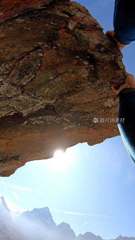 日出时，男性攀登者登上岩石顶峰