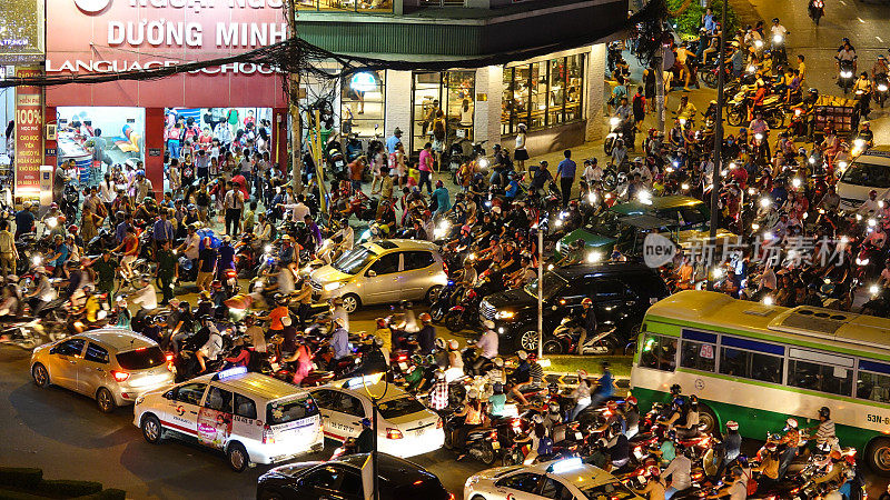航拍:无数的摩托车和汽车在拥挤的街道上缓慢行驶。