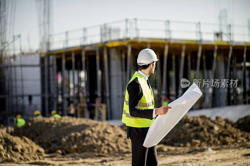 侧视图的年轻建筑工程师与项目和安全帽