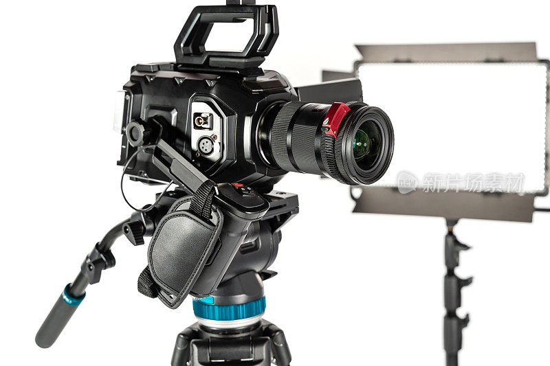 专业的电影摄像机在一个摄像机三脚架和一个照明LED面板在白色工作室背景