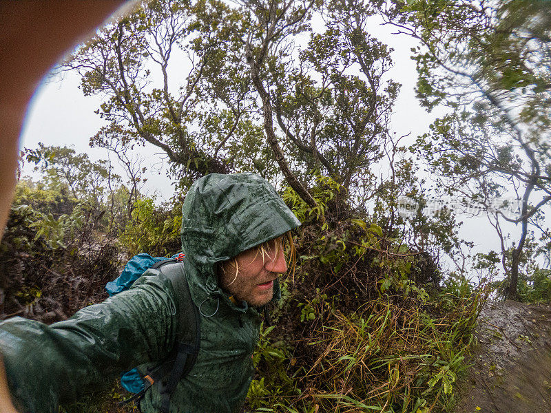 一名男子在夏威夷徒步旅行，在多雨的雨林中自拍