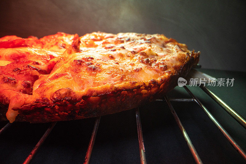 特写广角微距拍摄的美味烧焦的皮在热气腾腾的深盘皮辣香肠披萨新鲜出炉的烤箱在冷却架下加热灯与复制空间