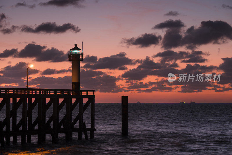 码头和灯塔，日落和戏剧性的天空-比利时海岸线，北海