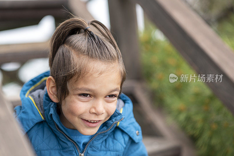 快乐的小男孩坐在木楼梯上