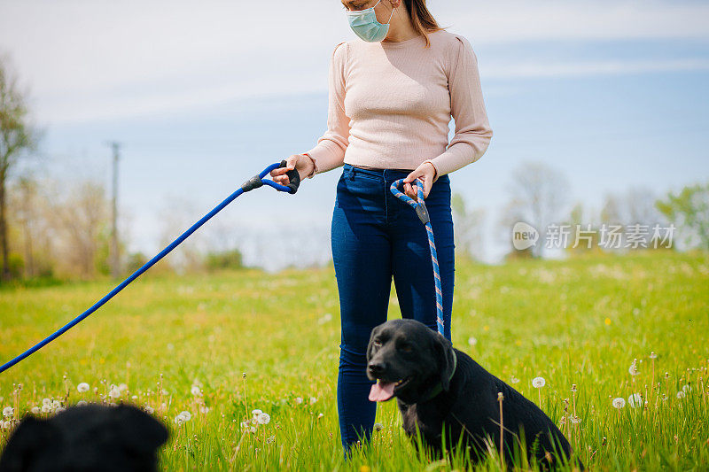 戴着防护面具带着狗在户外散步的女人