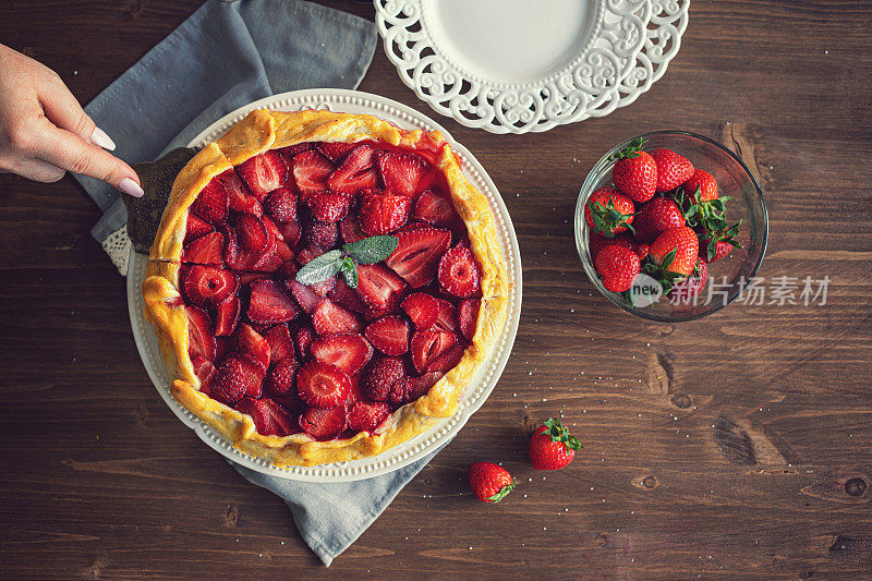 年轻女子准备草莓馅饼或打开的草莓派