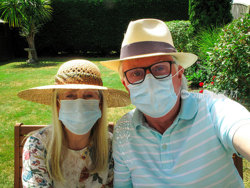 一对戴着防护面罩的老年夫妇在花园里一起自拍