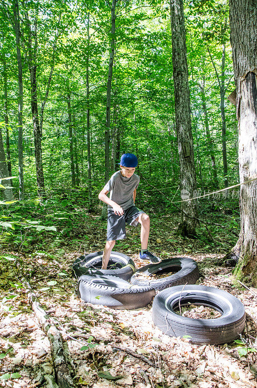 男孩在森林里踩着汽车轮胎奔跑