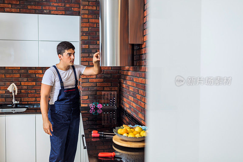 男电工带着夹板修理厨房抽油器过滤器