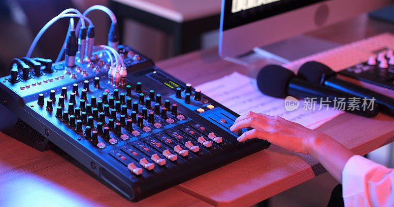 近距离的亚洲手制作人在混音板在精品录音棚工作。现代音乐录音棚控制台数字音频工作站软件。音乐制作的概念。