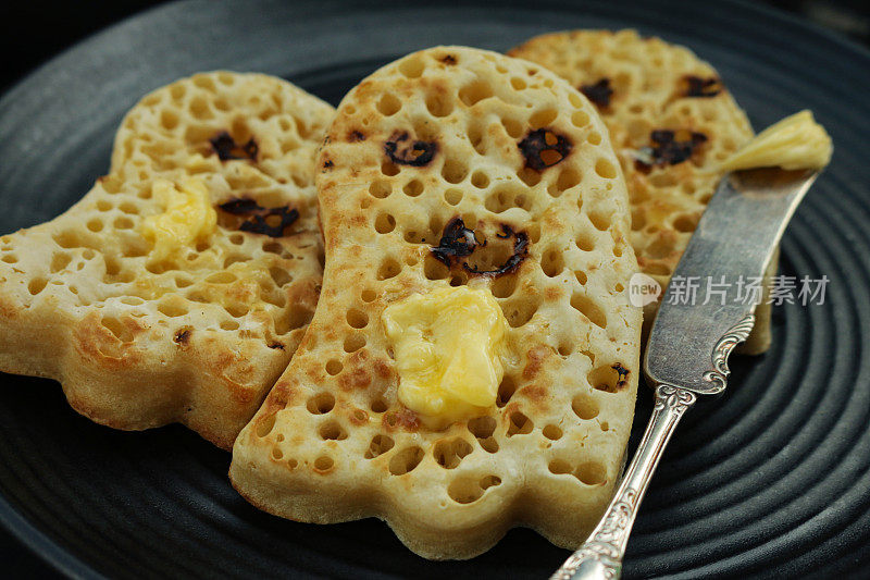 这是一个蓝色陶瓷盘子上涂着黄油的幽灵形状的黄油煎饼，这是儿童万圣节主题派对的食物创意