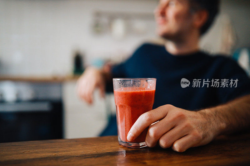 一个男人在家里吃水果奶昔当早餐