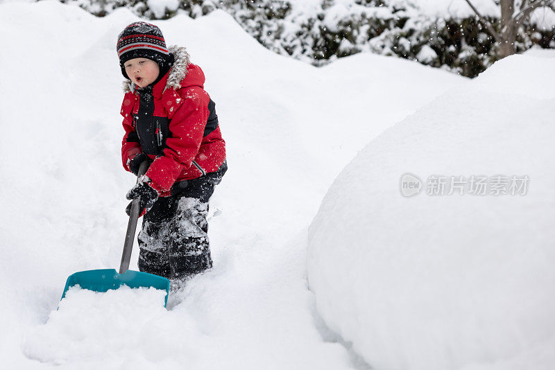 小男孩在冬季风暴后铲雪