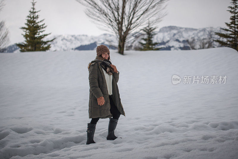 美丽的年轻女子走在堆积的雪地上