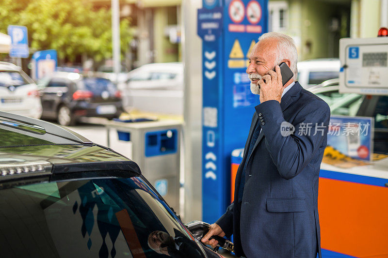 一位老人在加油站给他的车加油。