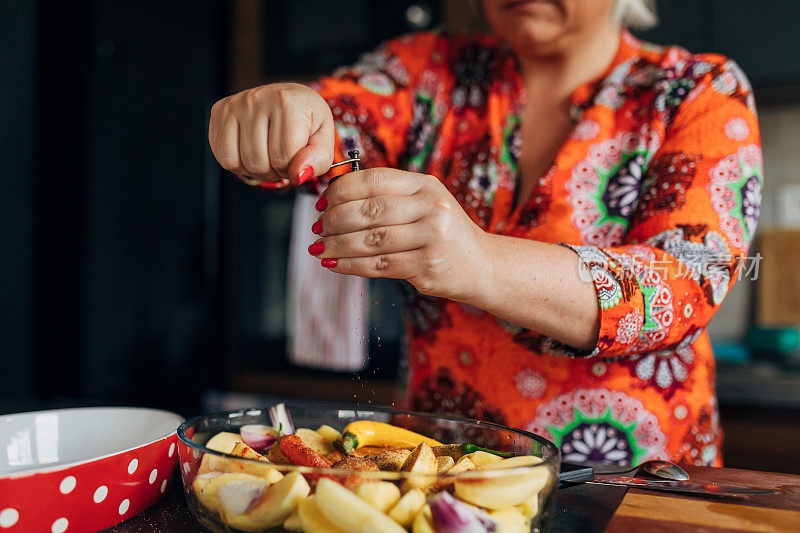 在她现代的厨房里准备午餐的时候，一位健康的女士用胡椒发调料做了一道素食菜
