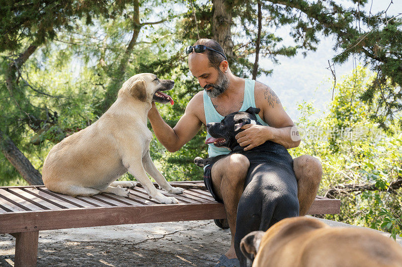 一个成熟的男人在他房子的花园里和他的狗玩耍