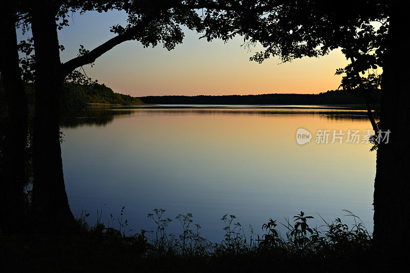 日落时分树木环绕的湖泊