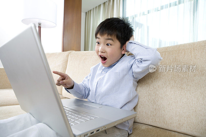 小男孩在沙发上用笔记本电脑上网