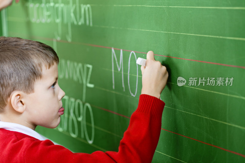 小男孩在黑板上写字，侧视图