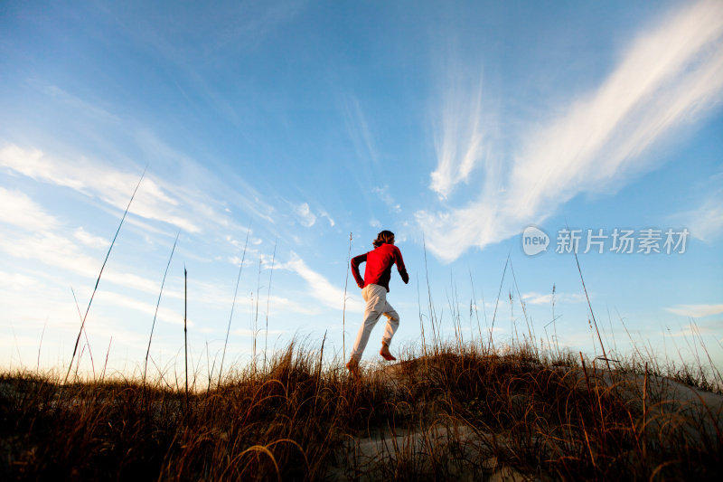 一个健康的年轻人在沙滩上赤脚跑步