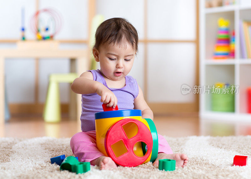 蹒跚学步的女孩在室内玩分类玩具坐在软