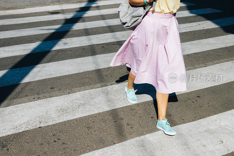 穿着粉色裙子和运动鞋的女孩正在过马路