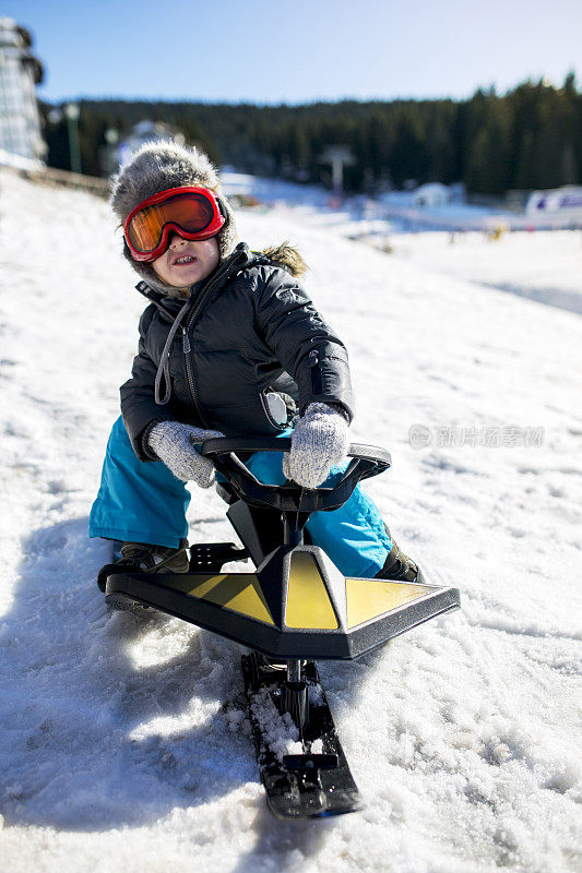孩子们穿着冬装在滑雪胜地的雪地摩托上。