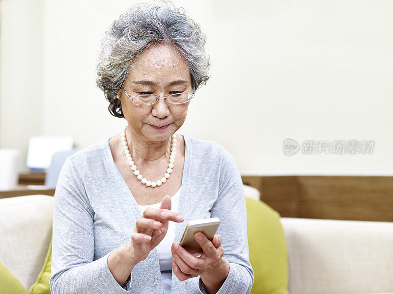 年长的亚洲女性使用手机