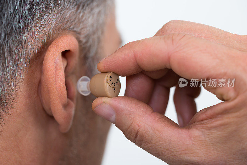 特写商人插入助听器在耳朵