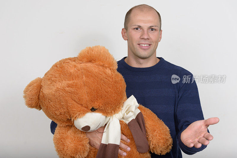 秃顶的年轻人抱着泰迪熊