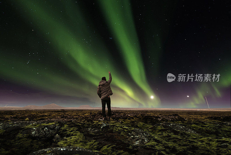 令人惊叹的美丽自然景观北极光，一个男人举起手臂，在冰岛旅行