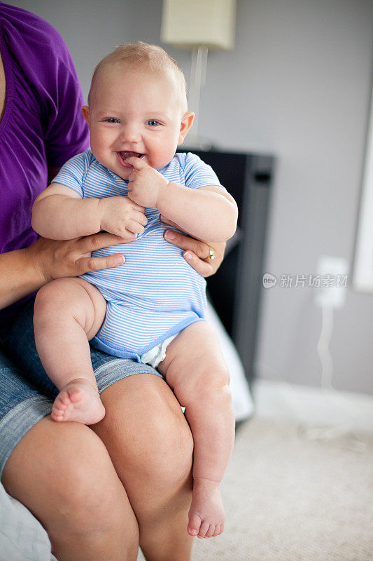 彩色图像的快乐婴儿被抱在大腿上