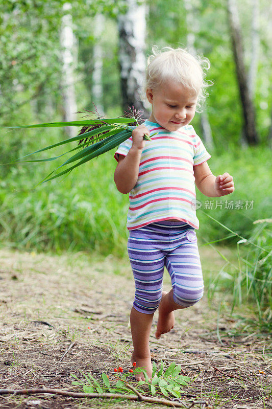 蹒跚学步的小女孩赤脚在森林里奔跑