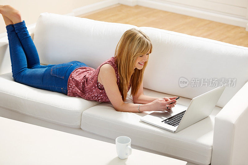 年轻女子躺在沙发上玩手机