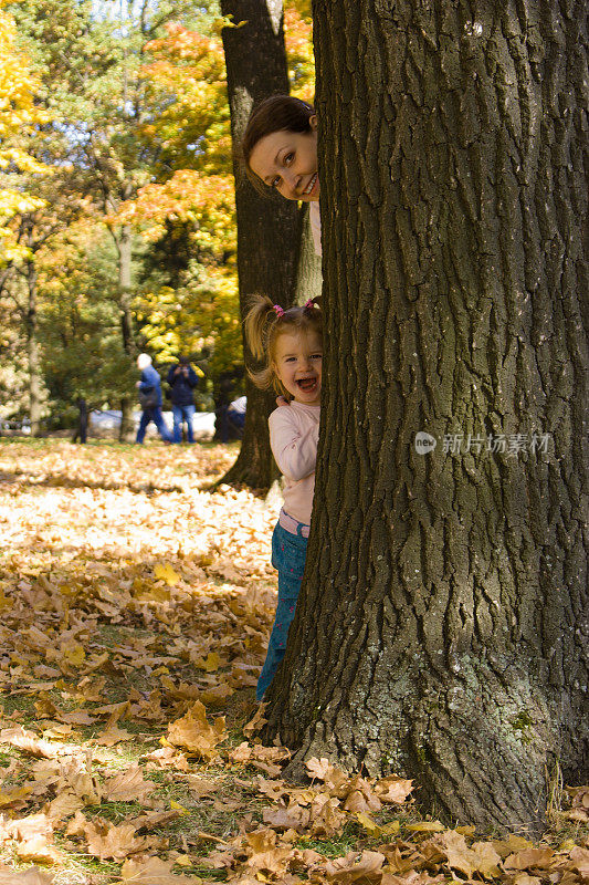 妈妈和小女孩躲在一棵树后面